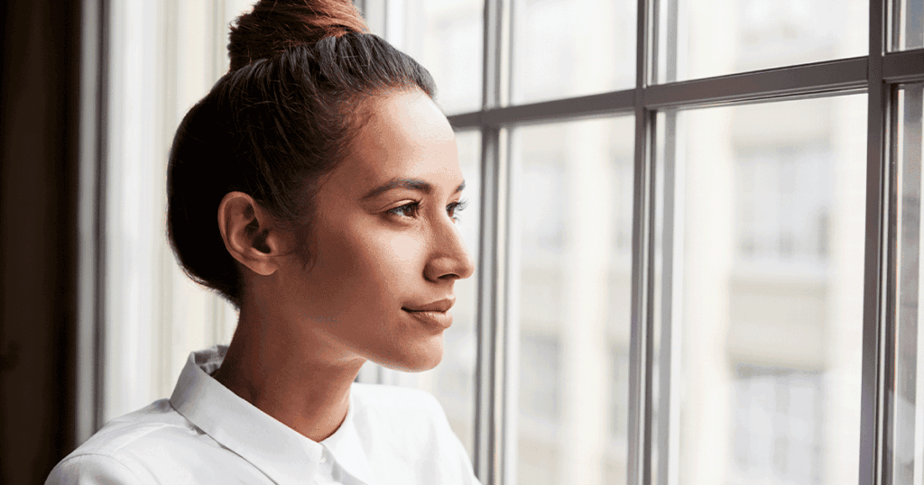 Woman looking out a window while preparing mentally and physically for childbirth.